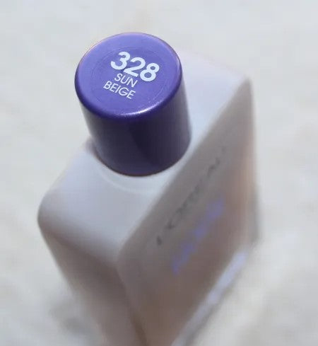 L'Oreal Paris Magic Nude Liquid Powder in Shade 328 Sun Beige. A 27ml glass bottle showcasing a warm, golden-beige liquid-to-powder foundation. The packaging features a signature purple cap and silver accents.