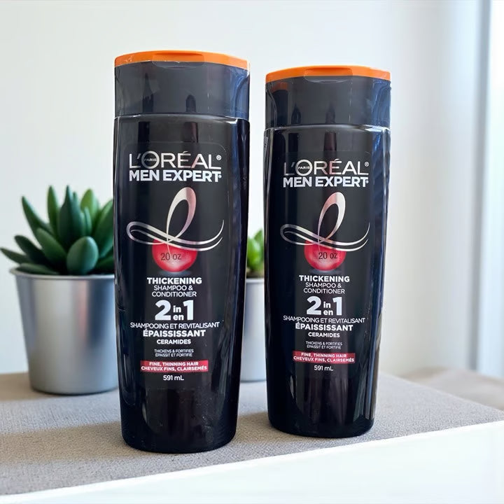 Two bottles of L'Oreal Men Expert 2-in-1 products on a surface with a plant in the background.